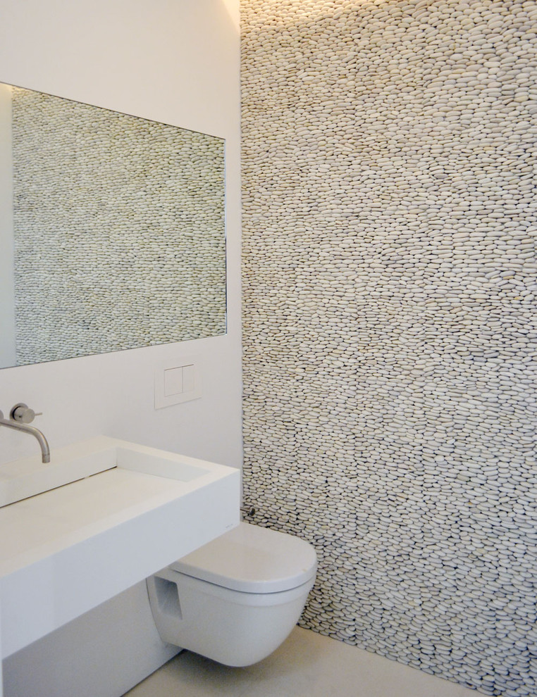 Modern powder room in New York with a wall-mount toilet and pebble tile.
