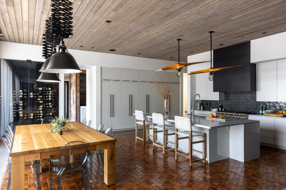Inspiration pour une grande salle à manger ouverte sur la cuisine chalet avec un mur blanc, tomettes au sol, un sol orange et un plafond en bois.