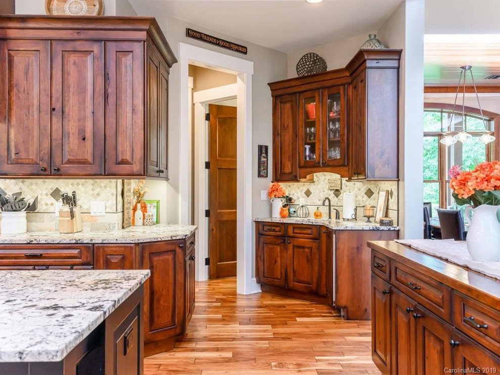 Inspiration for a rustic medium tone wood floor open concept kitchen remodel with a farmhouse sink, dark wood cabinets, granite countertops, beige backsplash, an island and white countertops