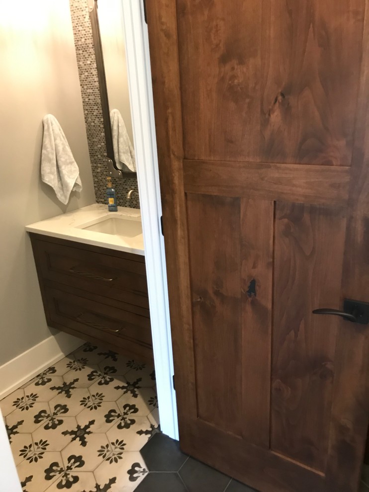 Photo of a transitional powder room in Grand Rapids with gray tile, ceramic tile, grey walls, ceramic floors, an undermount sink, engineered quartz benchtops, grey floor and white benchtops.