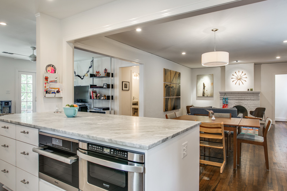 Small eclectic u-shaped open plan kitchen in Dallas with an undermount sink, flat-panel cabinets, white cabinets, marble benchtops, white splashback, ceramic splashback, stainless steel appliances, dark hardwood floors and with island.