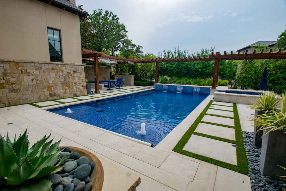 Photo of a mid-sized transitional backyard rectangular pool in Dallas with a water feature and natural stone pavers.