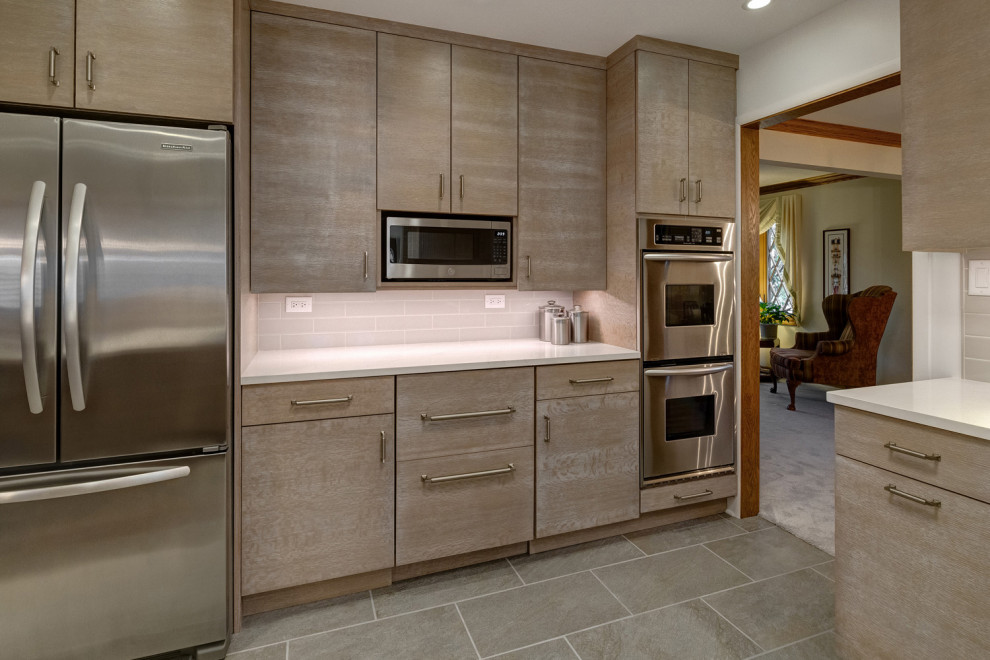 Photo of a mid-sized contemporary u-shaped eat-in kitchen in Chicago with a single-bowl sink, flat-panel cabinets, medium wood cabinets, quartz benchtops, grey splashback, porcelain splashback, stainless steel appliances, porcelain floors, a peninsula, multi-coloured floor and grey benchtop.