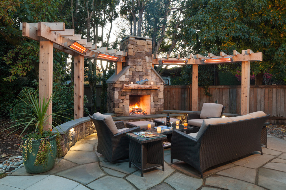 Country backyard patio in Seattle with natural stone pavers, no cover and with fireplace.