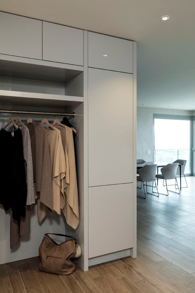 Small modern gender-neutral built-in wardrobe in Milan with flat-panel cabinets, beige cabinets and porcelain floors.