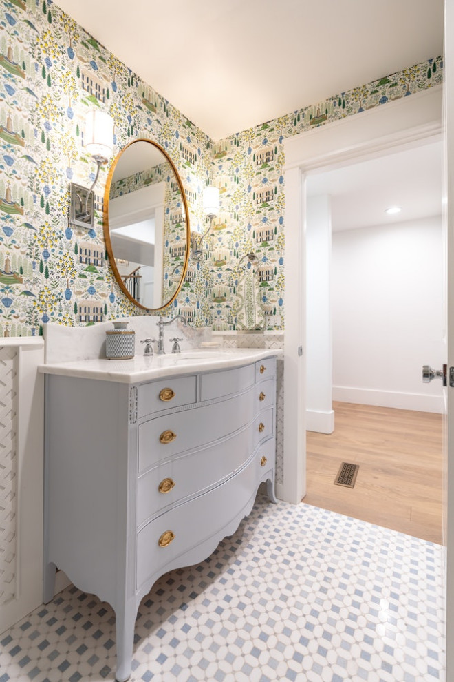 Classic cloakroom in Oklahoma City with blue cabinets, white walls, mosaic tile flooring, a submerged sink, marble worktops, blue floors, white worktops, a freestanding vanity unit and wallpapered walls.