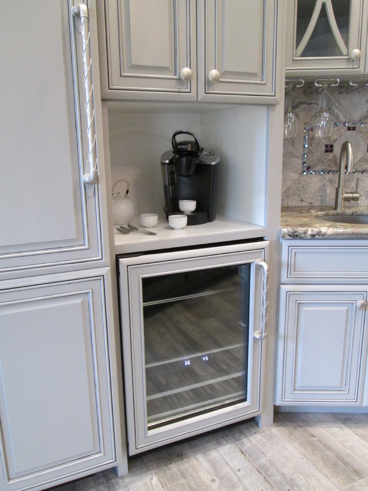 Open concept kitchen - huge transitional l-shaped porcelain tile open concept kitchen idea in Phoenix with an undermount sink, raised-panel cabinets, gray cabinets, granite countertops, gray backsplash, stone tile backsplash, stainless steel appliances and an island