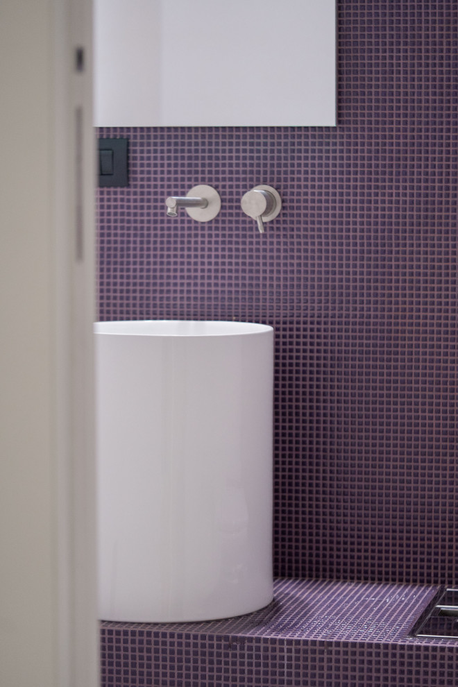 Inspiration för små moderna lila toaletter, med lila skåp, en toalettstol med hel cisternkåpa, mosaik, lila väggar, klinkergolv i keramik, ett piedestal handfat, kaklad bänkskiva och beiget golv