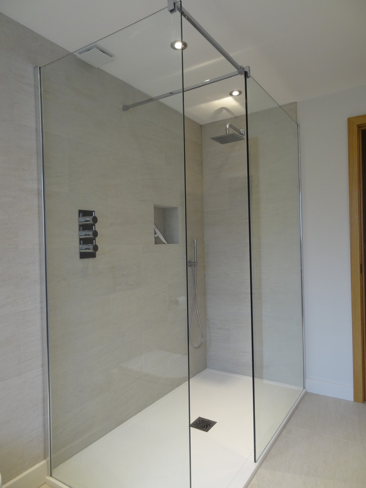 Design ideas for a medium sized modern family bathroom in London with glass-front cabinets, light wood cabinets, a freestanding bath, a corner shower, a one-piece toilet, beige tiles, ceramic tiles, grey walls and ceramic flooring.