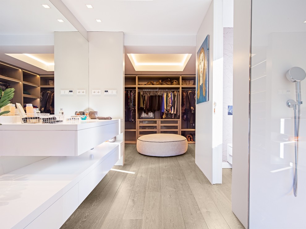 Photo of a large contemporary gender-neutral walk-in wardrobe in Madrid with open cabinets, medium wood cabinets and light hardwood floors.