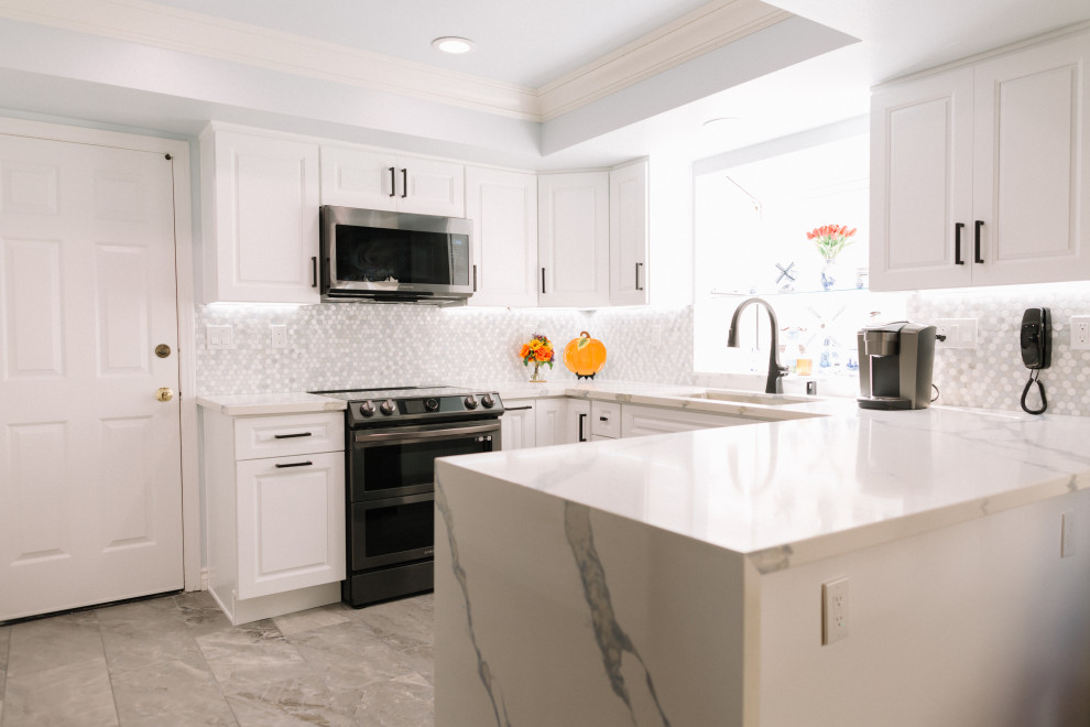 Foto på ett mellanstort funkis vit kök, med vita skåp, marmorbänkskiva, vitt stänkskydd, svarta vitvaror och en köksö