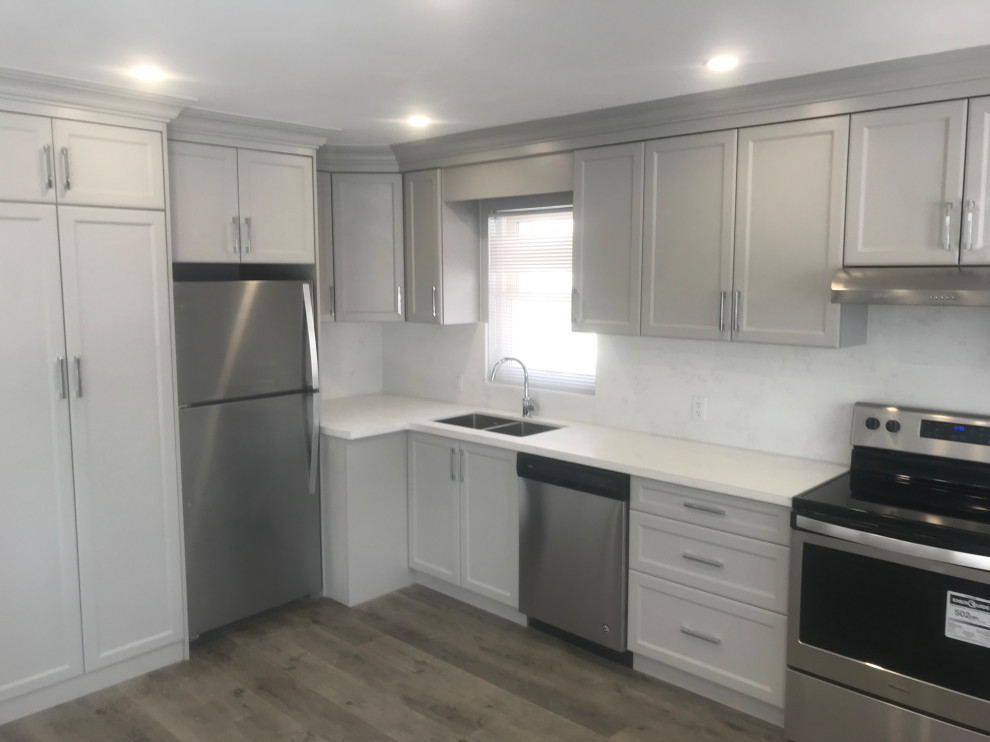 Mid-sized transitional l-shaped medium tone wood floor eat-in kitchen photo with an undermount sink, shaker cabinets, gray cabinets, quartz countertops, white backsplash, quartz backsplash, stainless steel appliances and white countertops