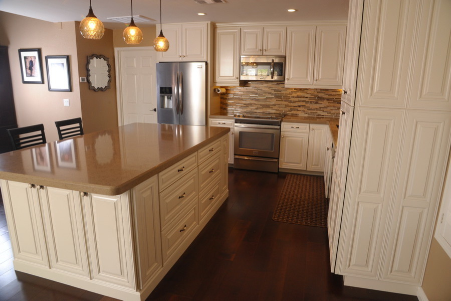 This is an example of a mid-sized traditional l-shaped separate kitchen in Phoenix with an undermount sink, raised-panel cabinets, white cabinets, limestone benchtops, beige splashback, matchstick tile splashback, stainless steel appliances, dark hardwood floors, with island, brown floor and beige benchtop.