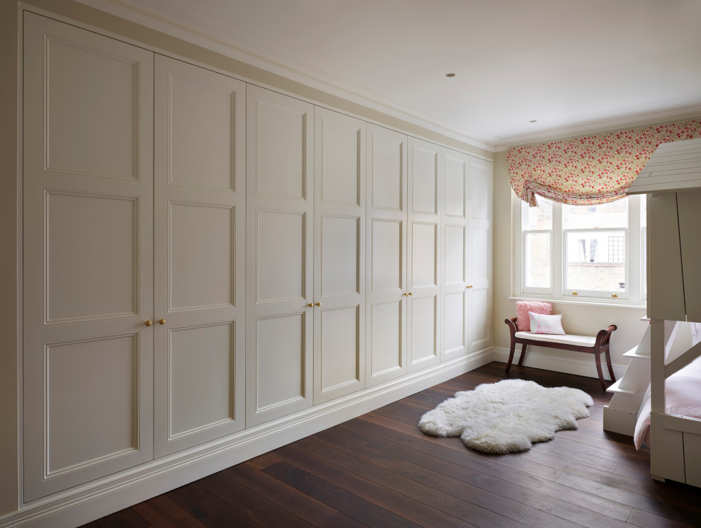 Inspiration for a large traditional gender-neutral built-in wardrobe in London with recessed-panel cabinets, white cabinets, dark hardwood floors and brown floor.