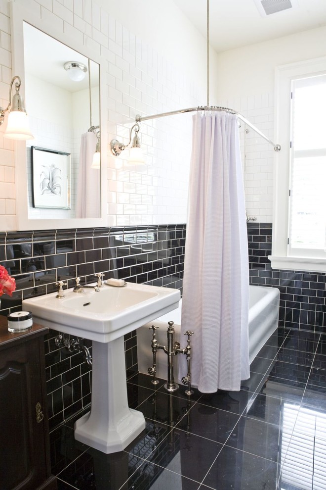 This is an example of a traditional bathroom in Calgary with a pedestal sink, dark wood cabinets, a shower/bathtub combo, black tile, subway tile and black floor.