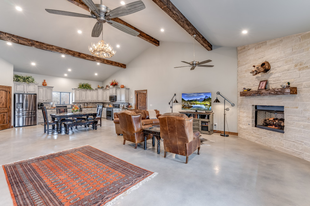 Photo of a mid-sized country open concept family room in Austin with grey walls, concrete floors, a standard fireplace, a stone fireplace surround, grey floor and vaulted.