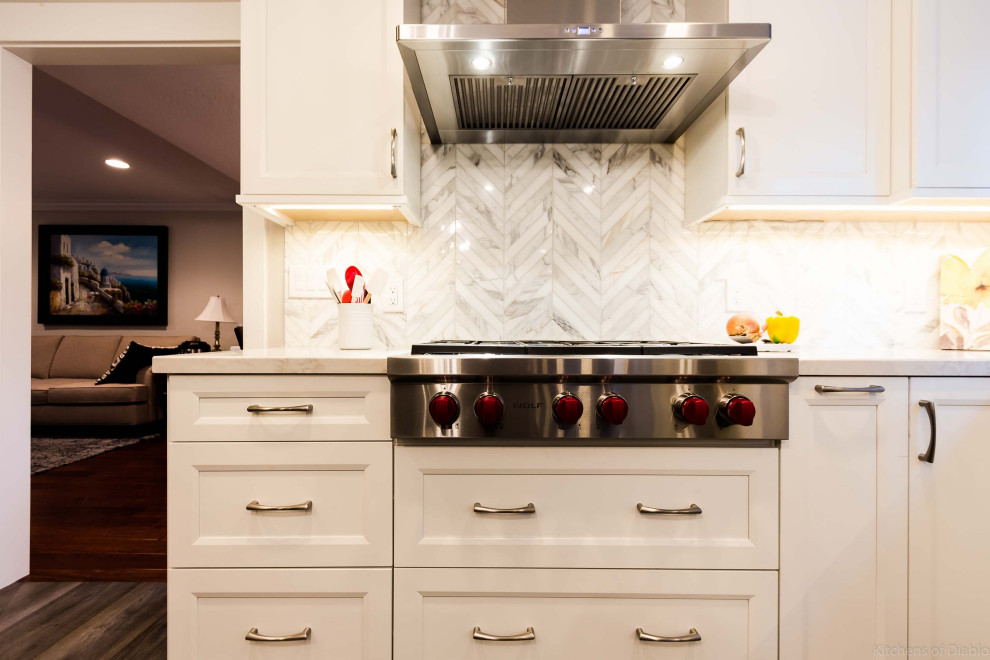 Open concept kitchen - large transitional u-shaped medium tone wood floor and gray floor open concept kitchen idea in San Francisco with an undermount sink, recessed-panel cabinets, white cabinets, quartz countertops, white backsplash, marble backsplash, stainless steel appliances, an island and white countertops