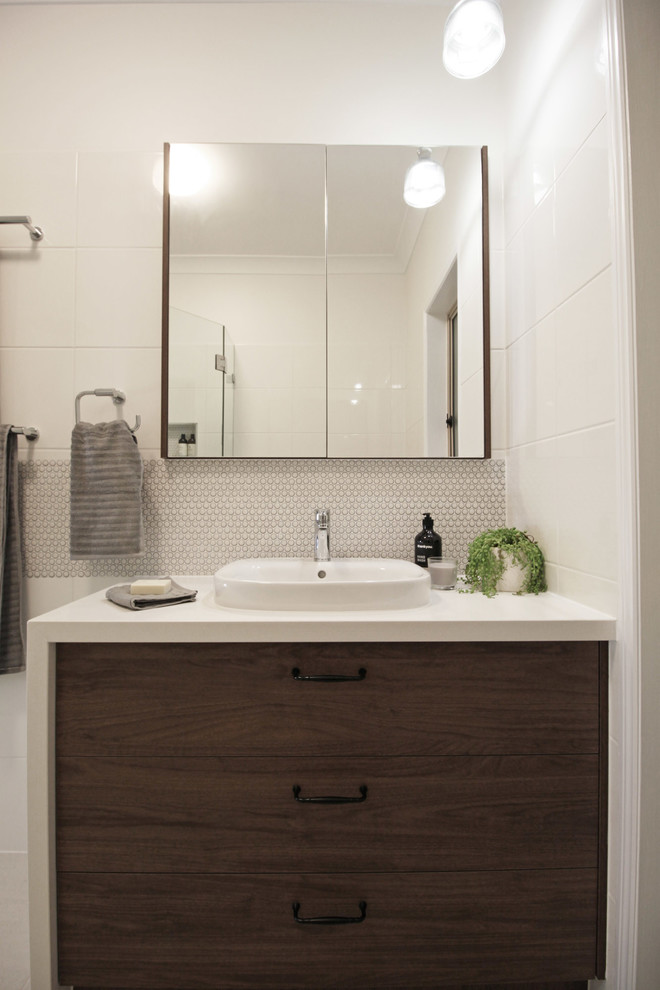 This is an example of a small contemporary master bathroom in Brisbane with flat-panel cabinets, dark wood cabinets, an alcove shower, a two-piece toilet, white tile, ceramic tile, white walls, porcelain floors, engineered quartz benchtops, beige floor, a hinged shower door and white benchtops.