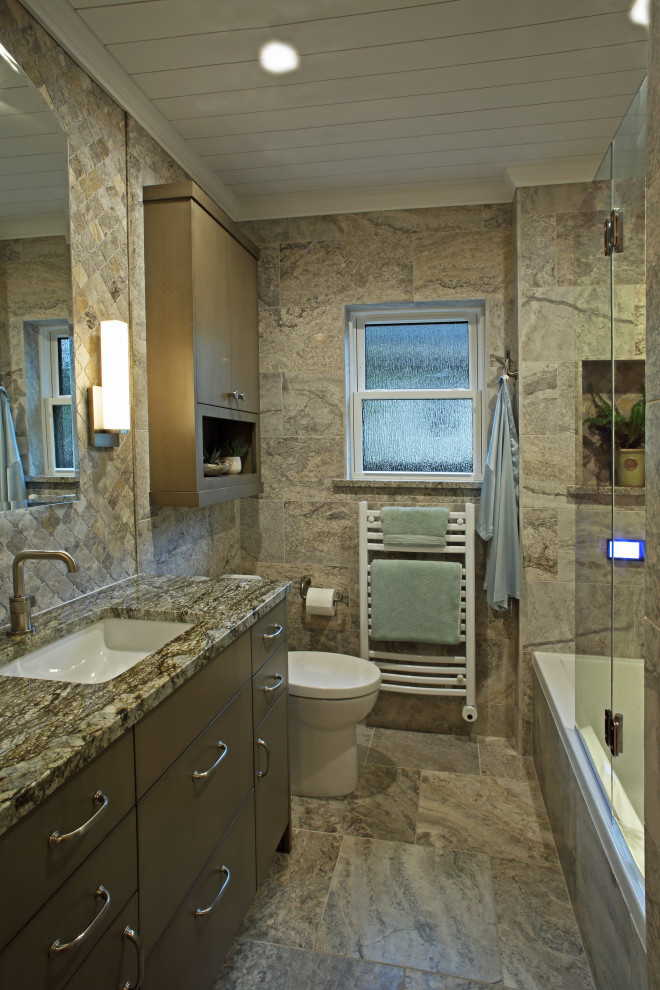 This is an example of a small modern 3/4 bathroom in Minneapolis with brown cabinets, a drop-in tub, travertine, multi-coloured walls, travertine floors, an undermount sink, granite benchtops, multi-coloured floor, flat-panel cabinets, a two-piece toilet, multi-coloured tile, a hinged shower door and multi-coloured benchtops.