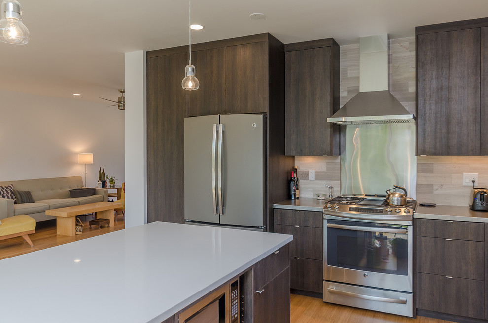 Mid-sized modern l-shaped open plan kitchen in Seattle with an integrated sink, flat-panel cabinets, dark wood cabinets, quartz benchtops, beige splashback, porcelain splashback, stainless steel appliances, bamboo floors and with island.
