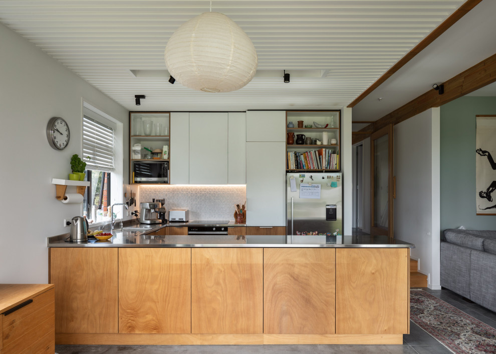 Inspiration for a mid-sized contemporary u-shaped eat-in kitchen in Auckland with an integrated sink, flat-panel cabinets, light wood cabinets, stainless steel benchtops, white splashback, ceramic splashback, stainless steel appliances, concrete floors, no island, grey floor, grey benchtop and coffered.