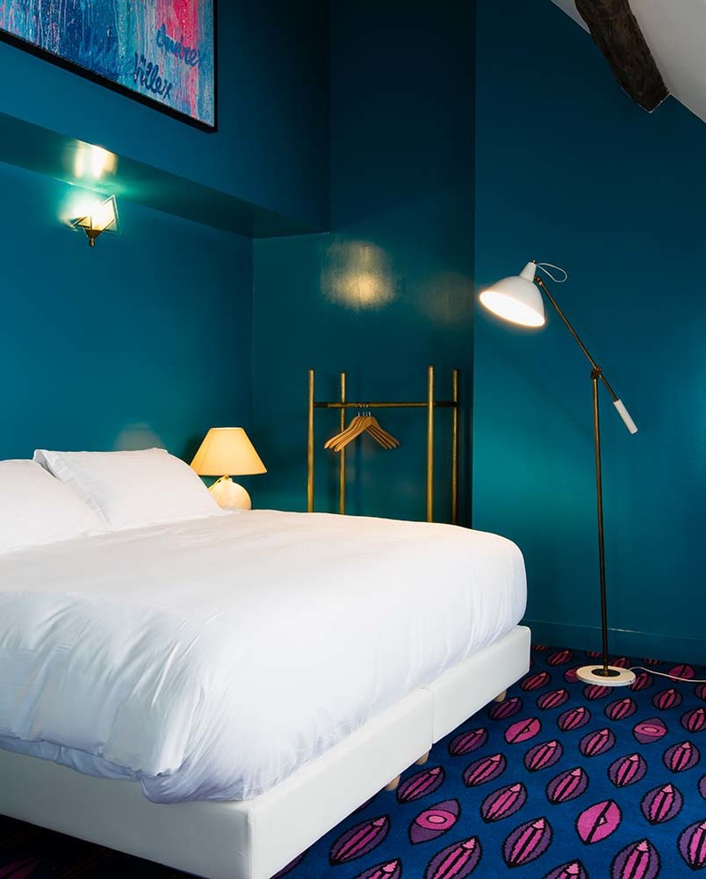 This is an example of a mid-sized contemporary bedroom in Paris with blue walls, carpet and no fireplace.