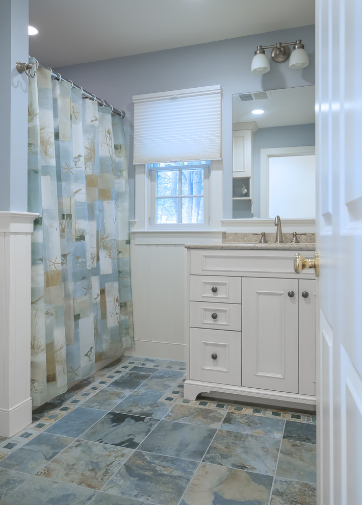 Design ideas for a mid-sized beach style 3/4 bathroom in Boston with raised-panel cabinets, white cabinets, a freestanding tub, a shower/bathtub combo, multi-coloured tile, ceramic tile, blue walls, ceramic floors, an undermount sink, granite benchtops and a two-piece toilet.