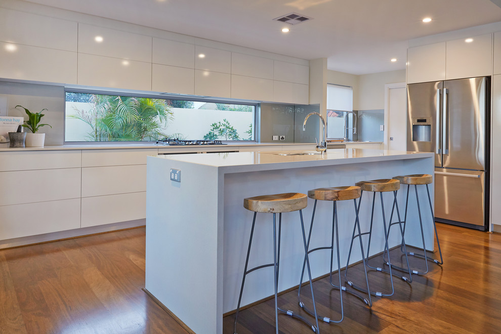 Contemporary kitchen in Perth with an undermount sink, flat-panel cabinets, white cabinets, quartz benchtops, metallic splashback, stainless steel appliances, medium hardwood floors and with island.