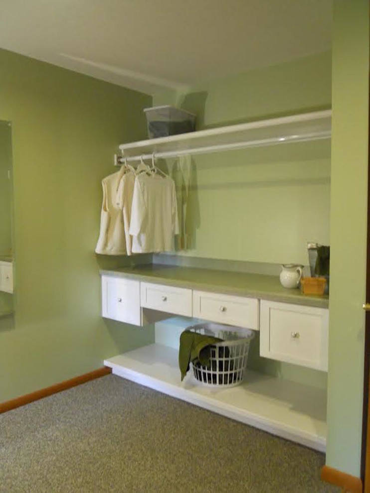 This is an example of a large traditional l-shaped utility room in Other with shaker cabinets, white cabinets, laminate benchtops, green walls, carpet, a side-by-side washer and dryer and green floor.