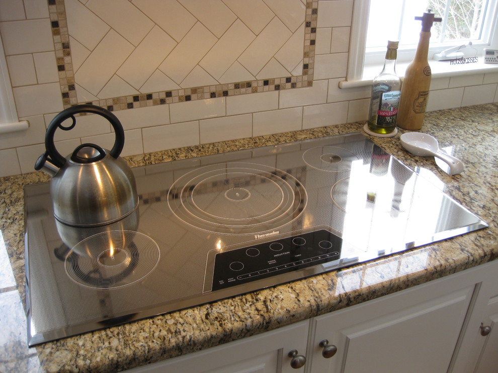 Eat-in kitchen - transitional u-shaped medium tone wood floor eat-in kitchen idea in Boston with an undermount sink, raised-panel cabinets, white cabinets, granite countertops, white backsplash, ceramic backsplash, stainless steel appliances, an island and beige countertops