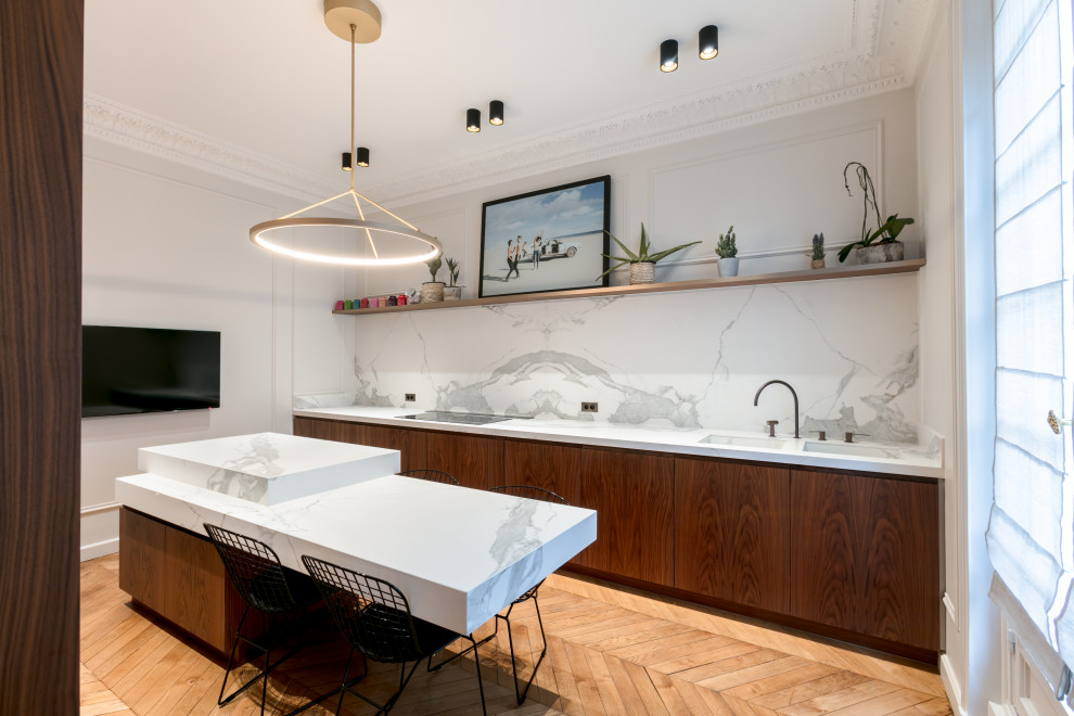 Inspiration for a contemporary galley kitchen in Paris with a double-bowl sink, flat-panel cabinets, dark wood cabinets, white splashback, stone slab splashback, medium hardwood floors, with island, brown floor and white benchtop.