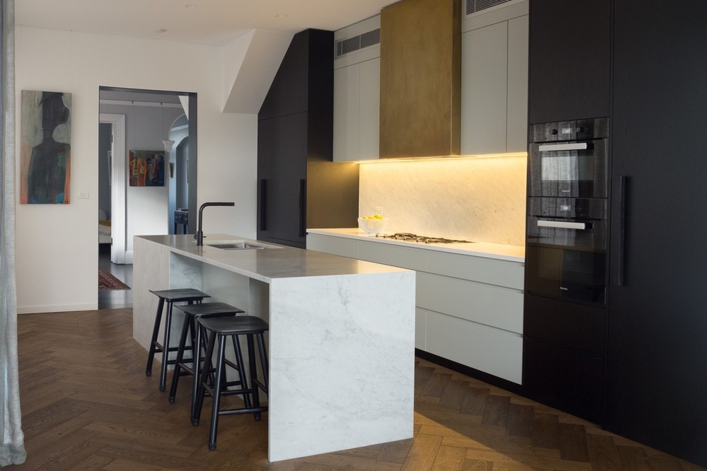 Large contemporary galley kitchen pantry in Sydney with an undermount sink, flat-panel cabinets, dark wood cabinets, marble benchtops, marble splashback, black appliances, medium hardwood floors and with island.