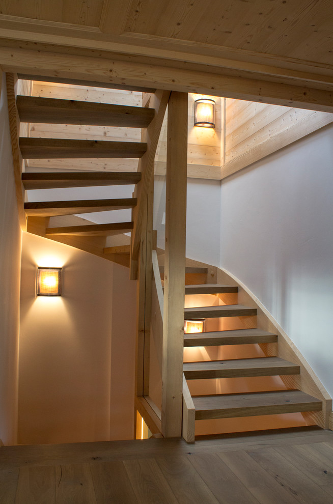 Photo of a country wood curved staircase in Other with open risers and wood railing.