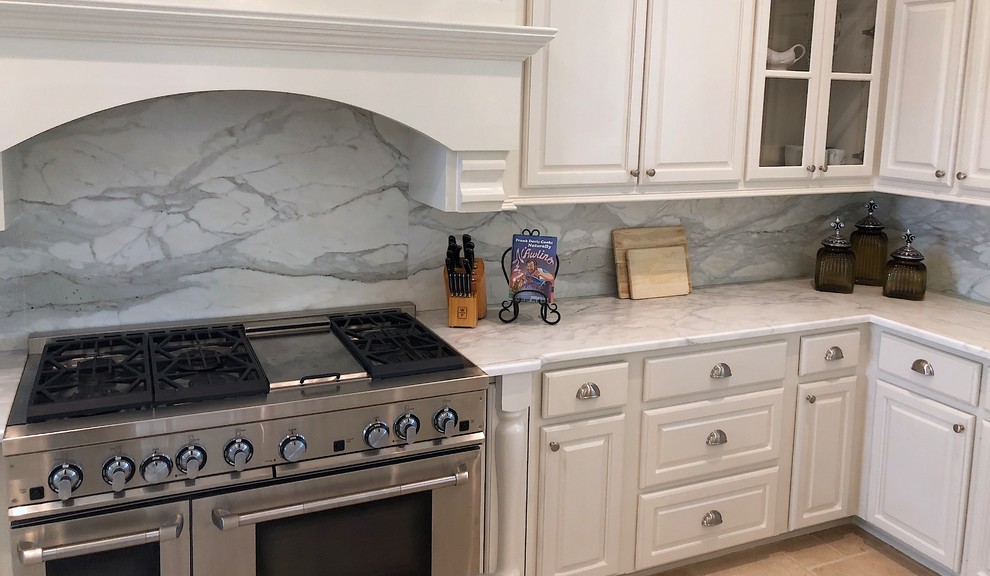 Example of a classic beige floor kitchen design in New Orleans with marble countertops, white backsplash, marble backsplash, an island and white countertops