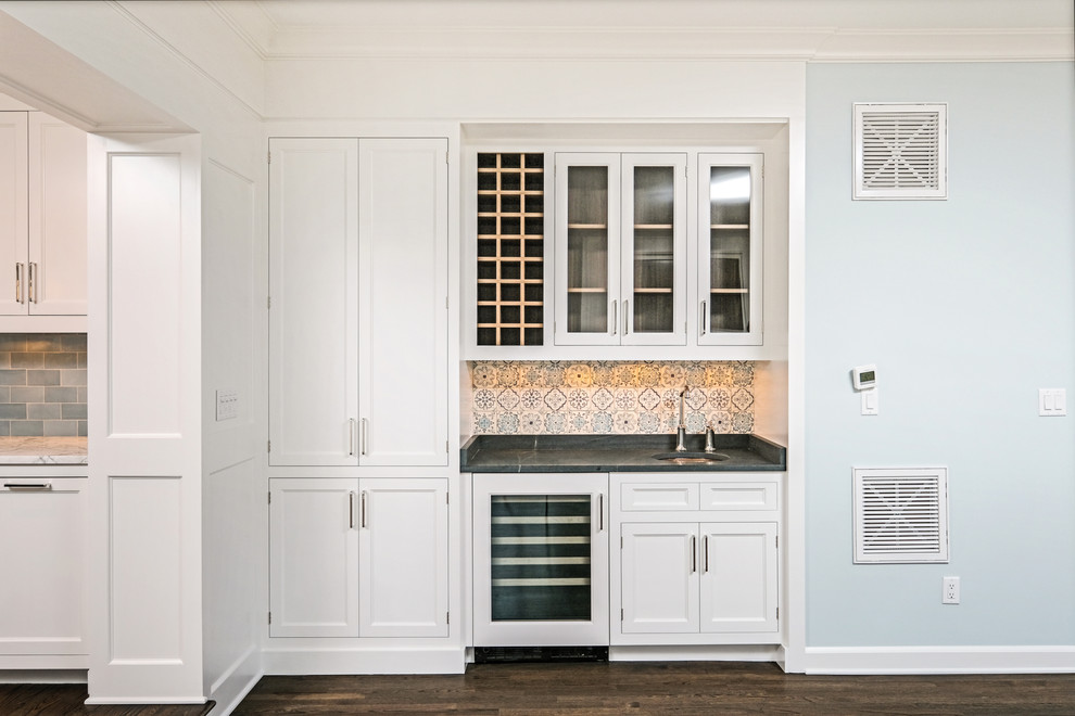 Design ideas for a small traditional single-wall wet bar in New York with an undermount sink, beaded inset cabinets, white cabinets, soapstone benchtops, multi-coloured splashback, terra-cotta splashback, dark hardwood floors and black benchtop.