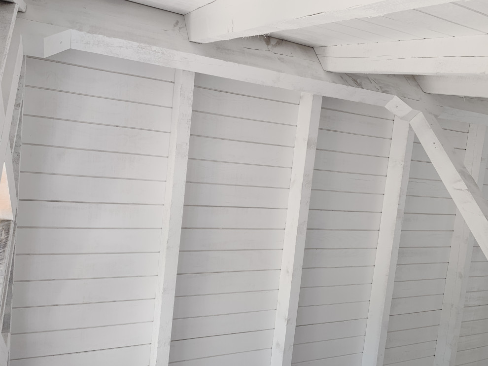 Kleines Uriges Wohnzimmer im Loft-Stil mit weißer Wandfarbe, hellem Holzboden, Kaminofen, Kaminumrandung aus Holzdielen, beigem Boden, gewölbter Decke und Holzdielenwänden in Minneapolis