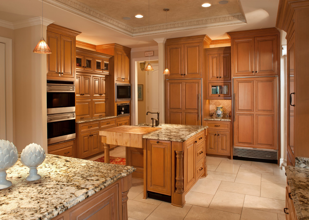 This is an example of a mediterranean u-shaped kitchen in Milwaukee with raised-panel cabinets, medium wood cabinets, beige splashback and panelled appliances.