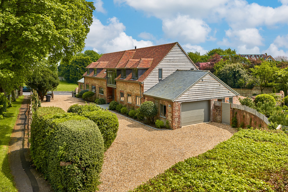 This is an example of a country two-storey brick brown house exterior in Hampshire with a gable roof.