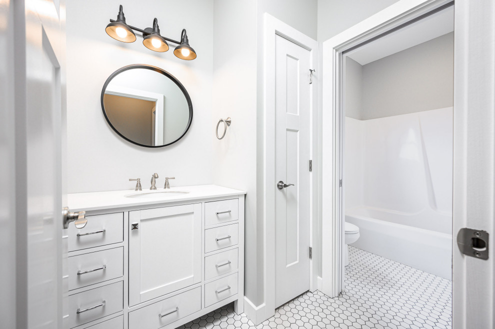 Example of a transitional ceramic tile and white floor tub/shower combo design with white cabinets, gray walls, an undermount sink, white countertops and furniture-like cabinets