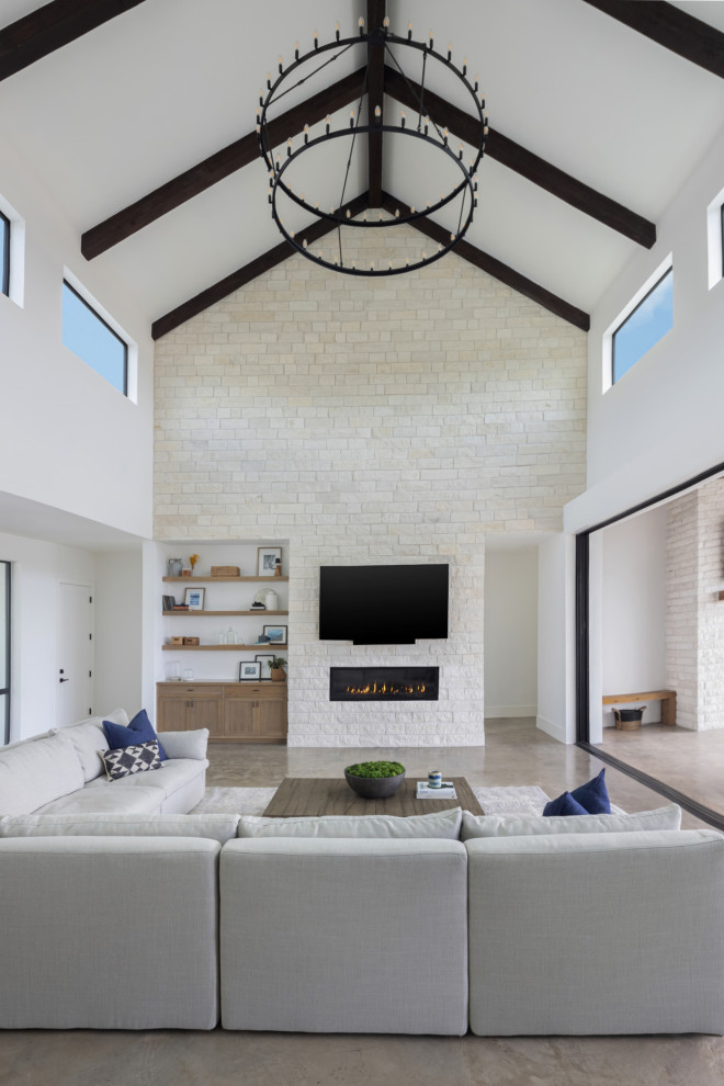 Inspiration for a large scandinavian open concept living room in Austin with white walls, concrete floors, a ribbon fireplace, a stone fireplace surround, a wall-mounted tv, beige floor and exposed beam.
