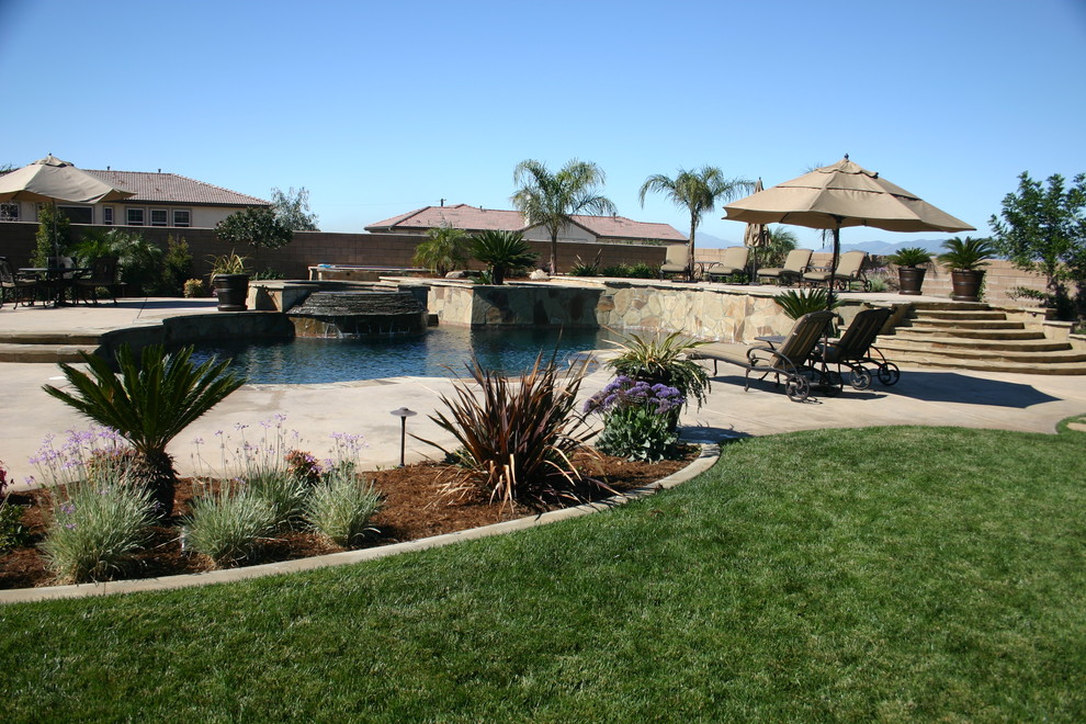 Design ideas for a large tropical backyard custom-shaped natural pool in Los Angeles with a hot tub and concrete pavers.