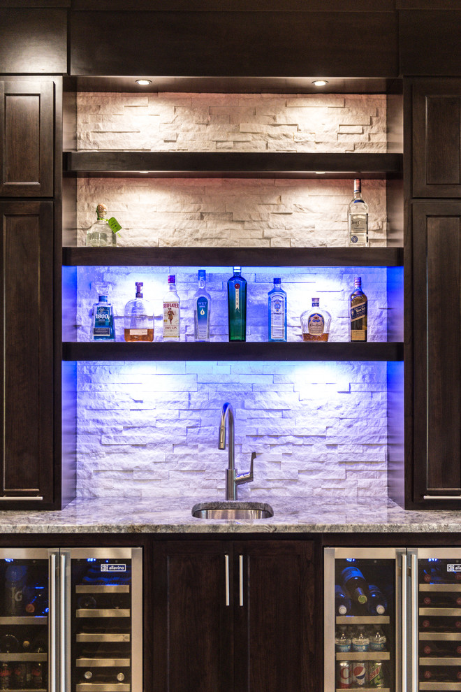 Inspiration for an expansive contemporary single-wall wet bar in Chicago with an undermount sink, shaker cabinets, dark wood cabinets, granite benchtops, white splashback, stone tile splashback and light hardwood floors.