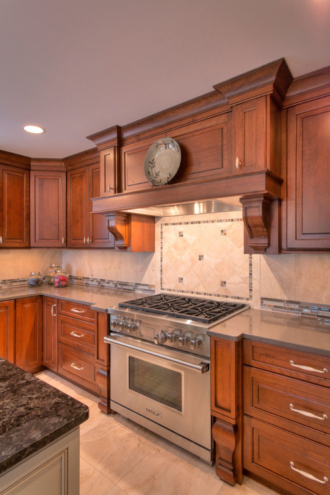 Example of a large transitional l-shaped ceramic tile eat-in kitchen design with an undermount sink, raised-panel cabinets, medium tone wood cabinets, multicolored backsplash, mosaic tile backsplash, paneled appliances and an island