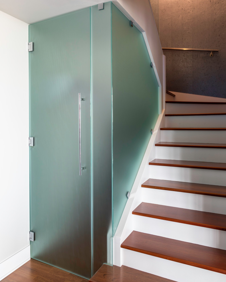 Идея дизайна: изогнутая лестница в современном стиле с деревянными ступенями, крашенными деревянными подступенками, металлическими перилами и обоями на стенах