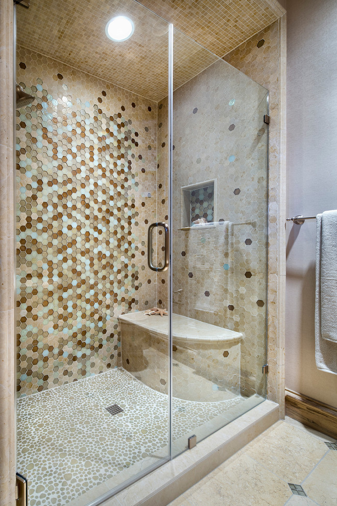 This is an example of a mid-sized mediterranean bathroom in Houston with recessed-panel cabinets, light wood cabinets, multi-coloured tile, mosaic tile, multi-coloured walls, beige floor, an alcove shower, pebble tile floors, a drop-in sink, a hinged shower door and pink benchtops.