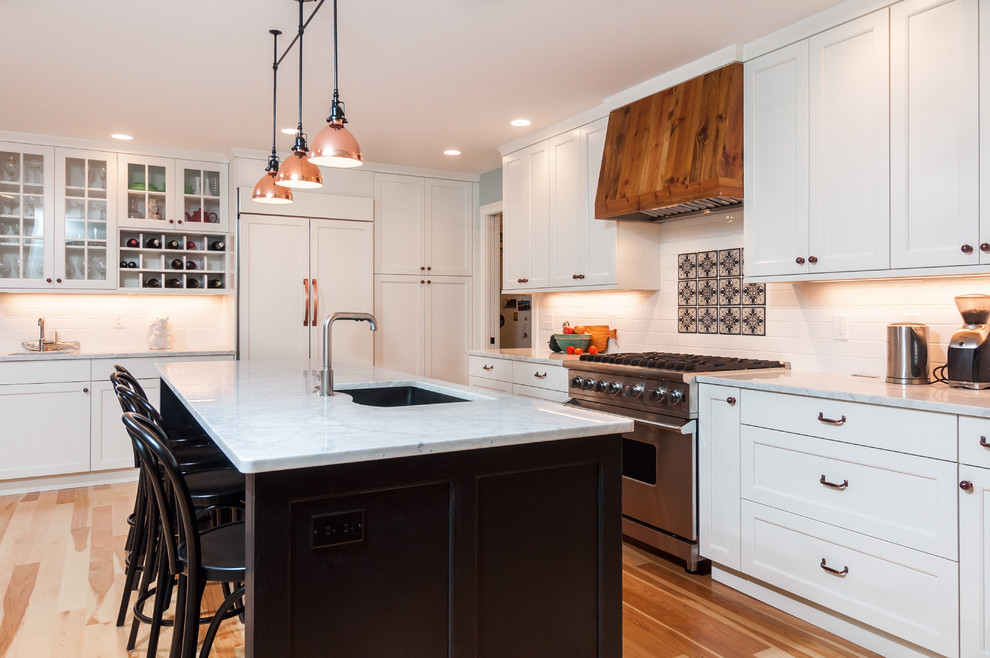 Mid-sized transitional l-shaped kitchen in Detroit with an undermount sink, shaker cabinets, white cabinets, white splashback, subway tile splashback, stainless steel appliances, medium hardwood floors, with island, granite benchtops and brown floor.