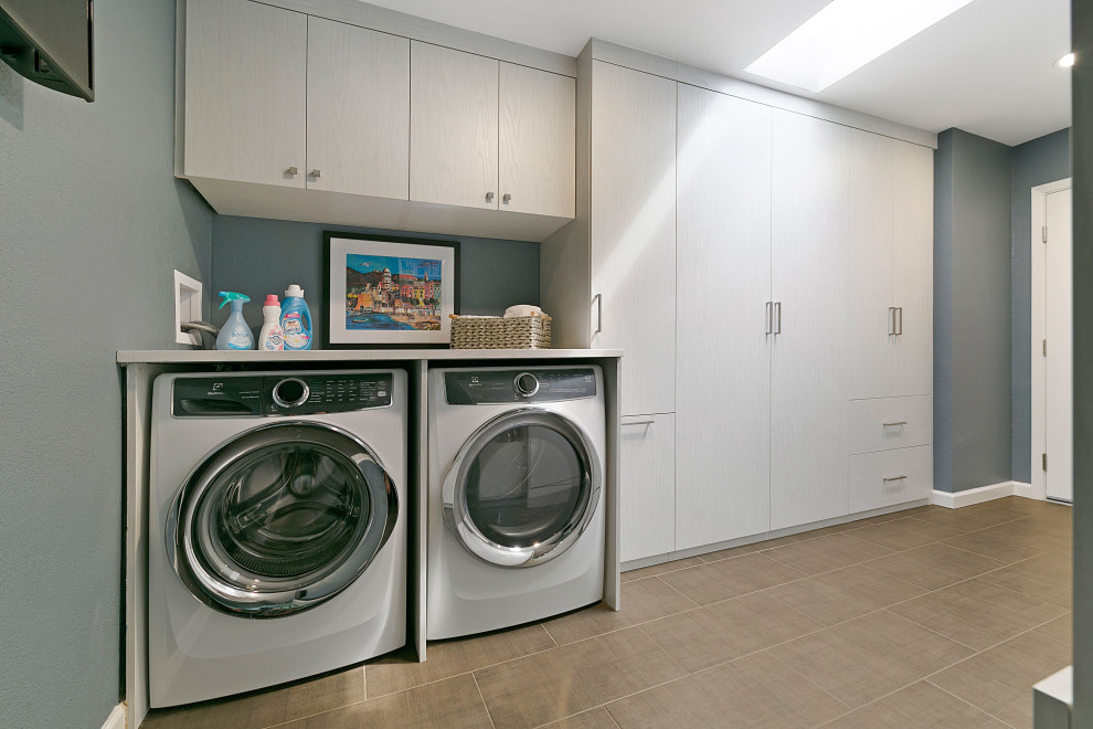 Immagine di una piccola lavanderia con pareti bianche, pavimento in laminato e pavimento grigio