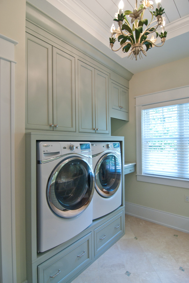 Photo of a large galley dedicated laundry room in Grand Rapids with recessed-panel cabinets, green cabinets, quartz benchtops, an integrated washer and dryer, beige benchtop, a farmhouse sink, yellow walls, porcelain floors, beige floor, blue splashback, mosaic tile splashback and timber.