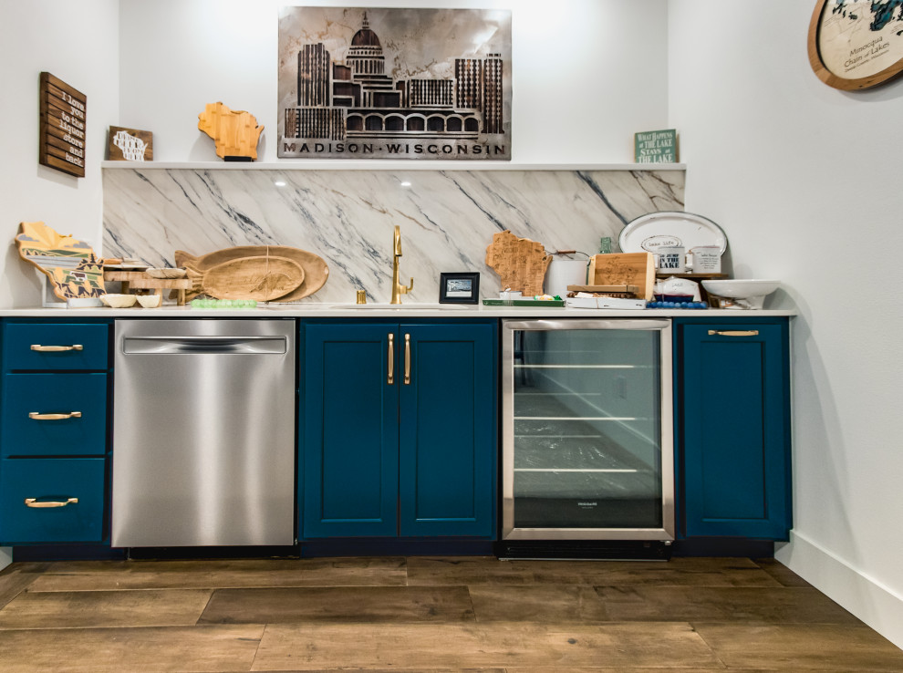 Inspiration for a traditional single-wall wet bar in Other with an undermount sink, recessed-panel cabinets, blue cabinets, solid surface benchtops, multi-coloured splashback, stone slab splashback, medium hardwood floors, brown floor and white benchtop.
