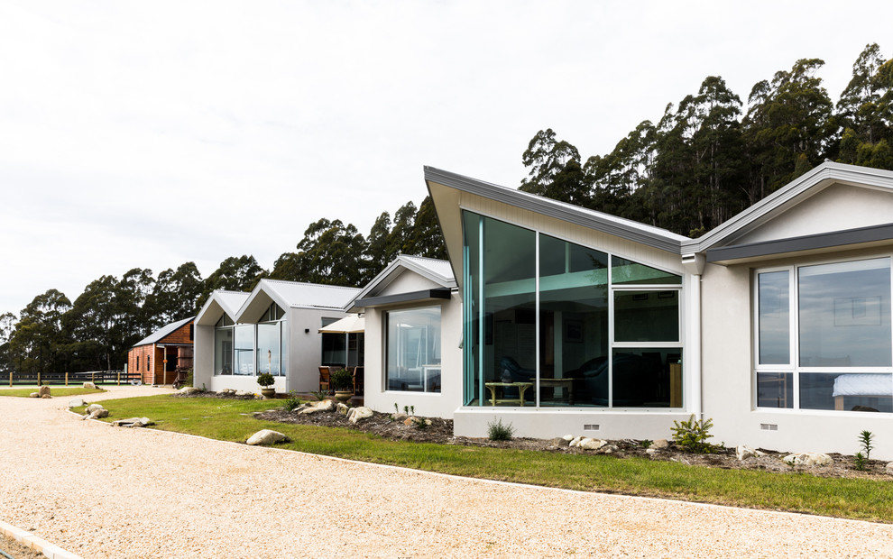 Contemporary one-storey stucco white house exterior in Hobart with a gable roof and a metal roof.